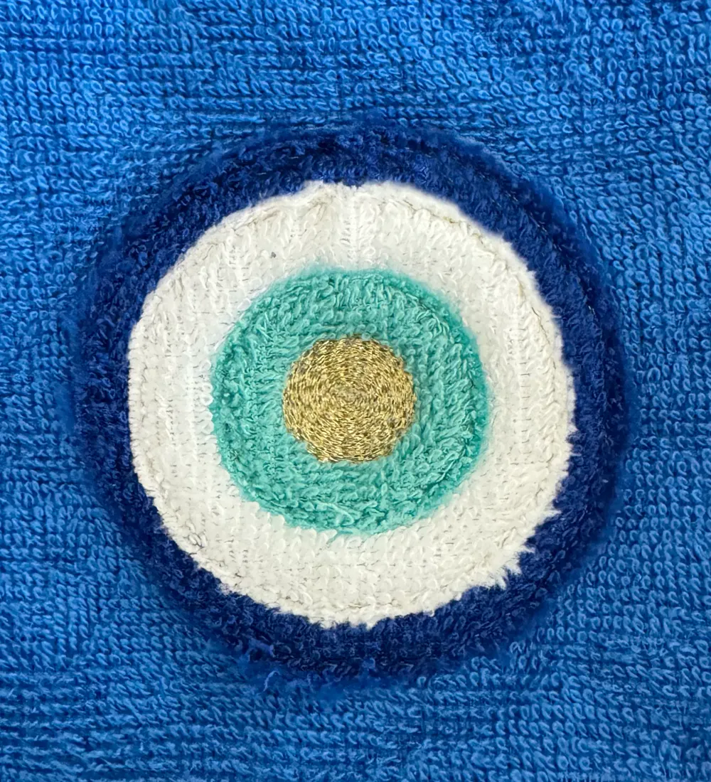 Œil protecteur en appliqué d'éponges blanche, turquoise et bleu nuit sur éponge bleue, centre brodé au fil doré