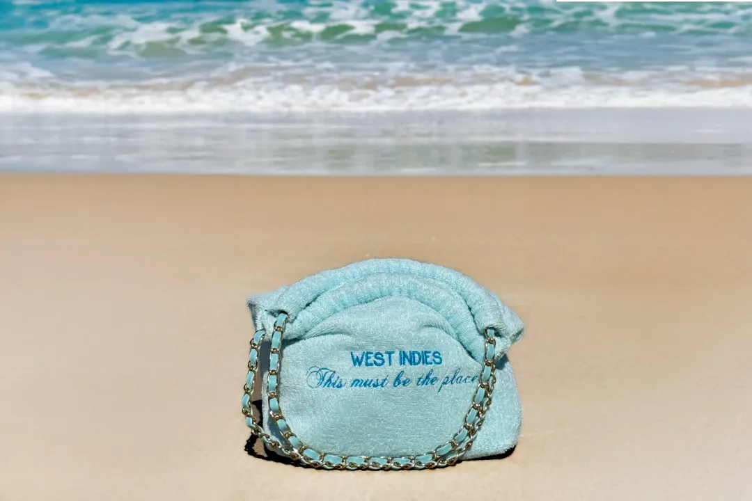 Balagan turquoise en éponge brodé « West Indies, This must be the place », posé sur le sable